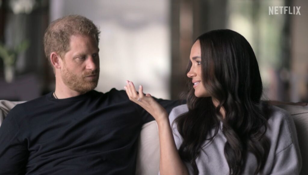 Prince Harry looking at Meghan Markle as she speaks in Netflix series