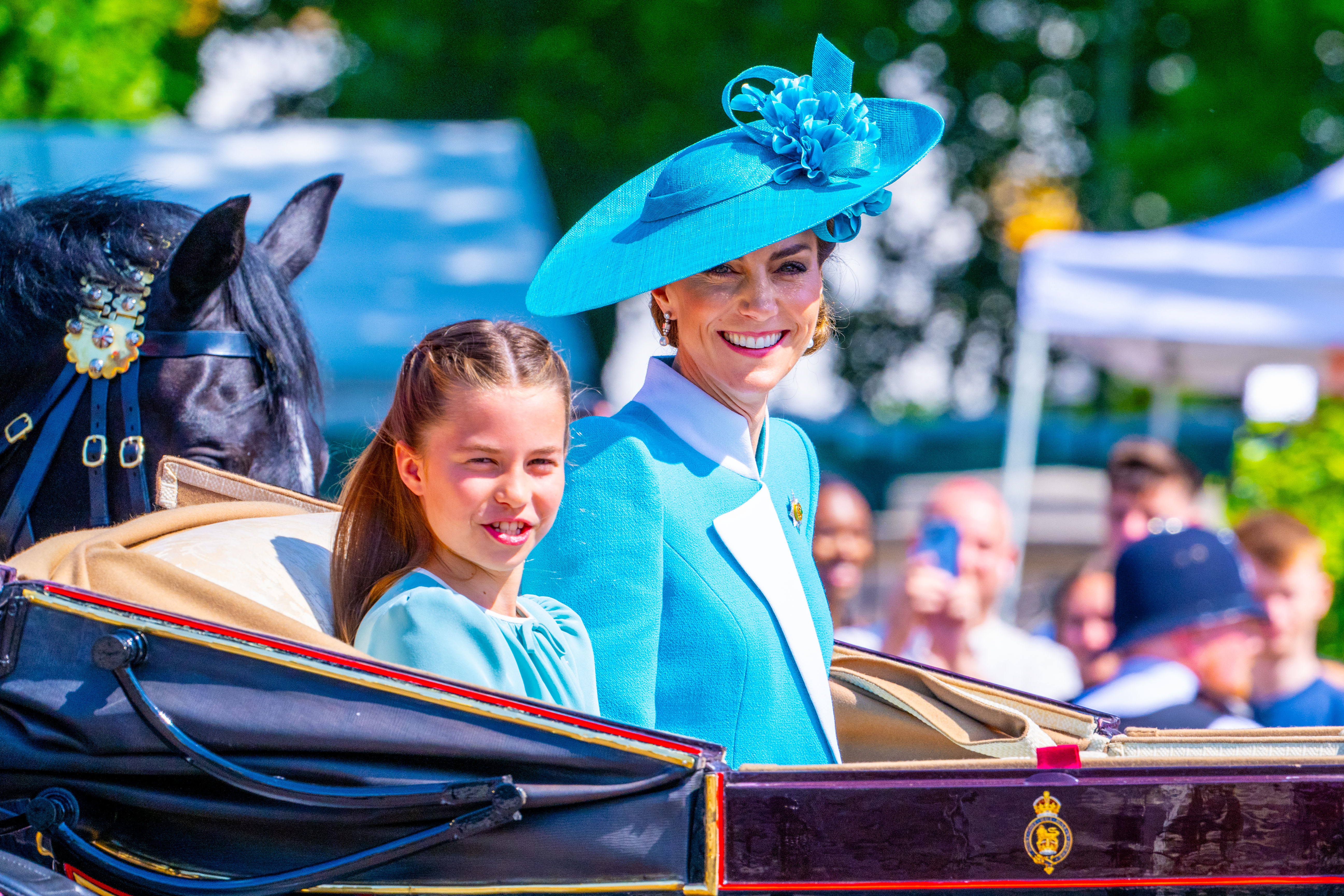 Princess Charlotte and Princess Kate Middleton riding in a carriage together, smiling