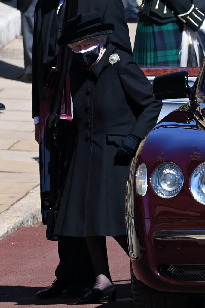 Queen Elizabeth wearing all black, including a black mask, exiting a vehicle as she arrived at Prince Philip's funeral