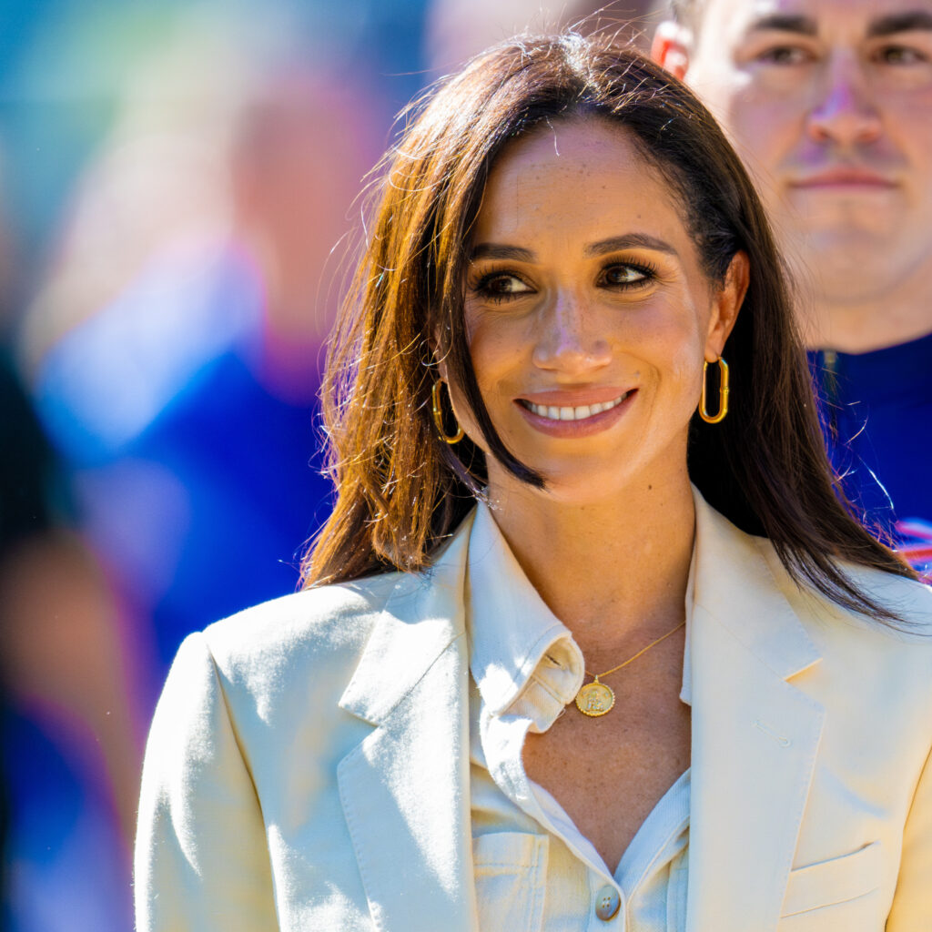 Meghan Markle walking and smiling in all-white outfit