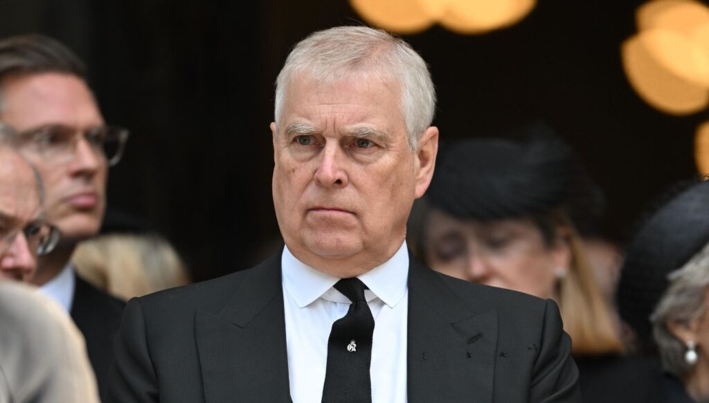 Prince Andrew looking serious in a black suit and tie