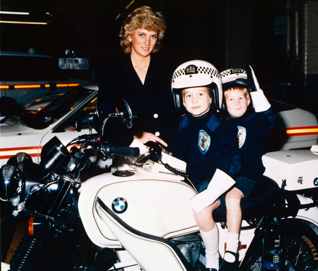 PRINCESS DIANA WITH PRINCE WILLIAM AND PRINCE HARRY. AT BRITISH TRANSPORT POLICE 1987, Prince William and Harry are dressed up as police officers and perched on a motorbike beside Diana