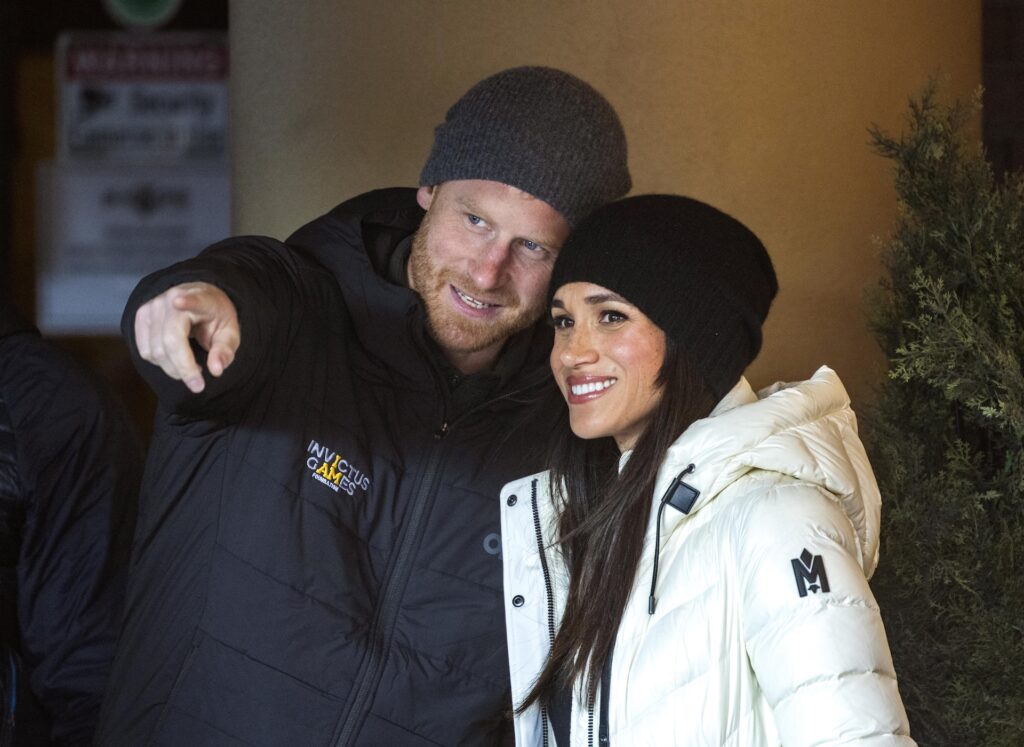 Prince Harry and Meghan Markle close together smiling in coats and hats