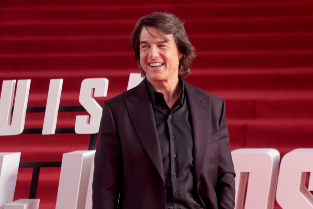 Tom Cruise at an event smiling in suit