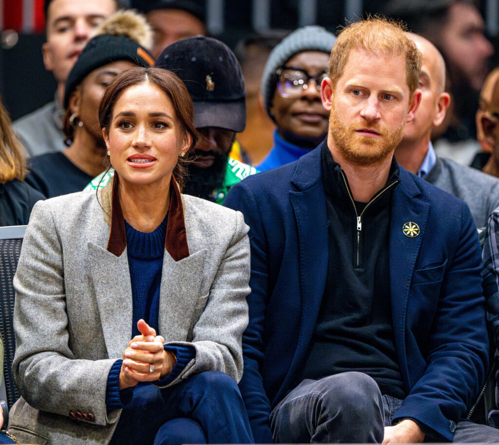 Meghan Markle and Prince Harry frowning whilst sat in the Invictus Games audience