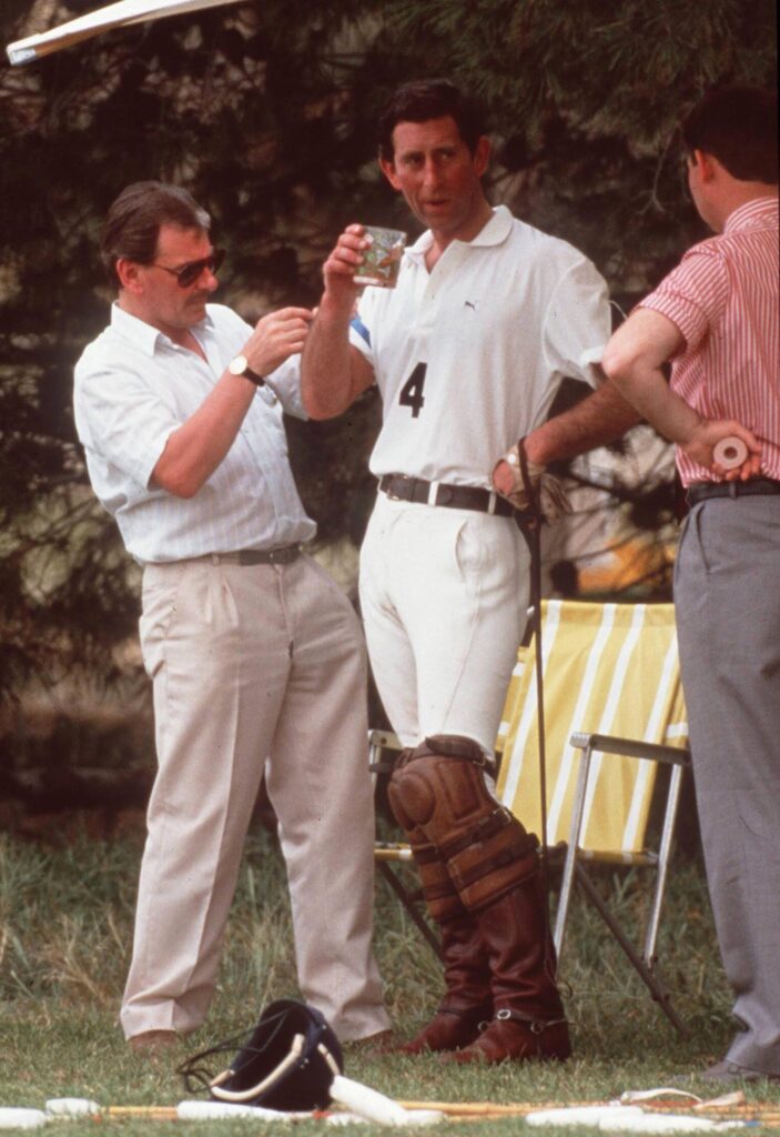 Prince Charles with his hand on his hip, having a drink whilst sporting his polo uniform