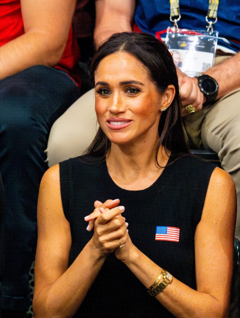 Meghan Markle clasping her hands while sitting down watching an event