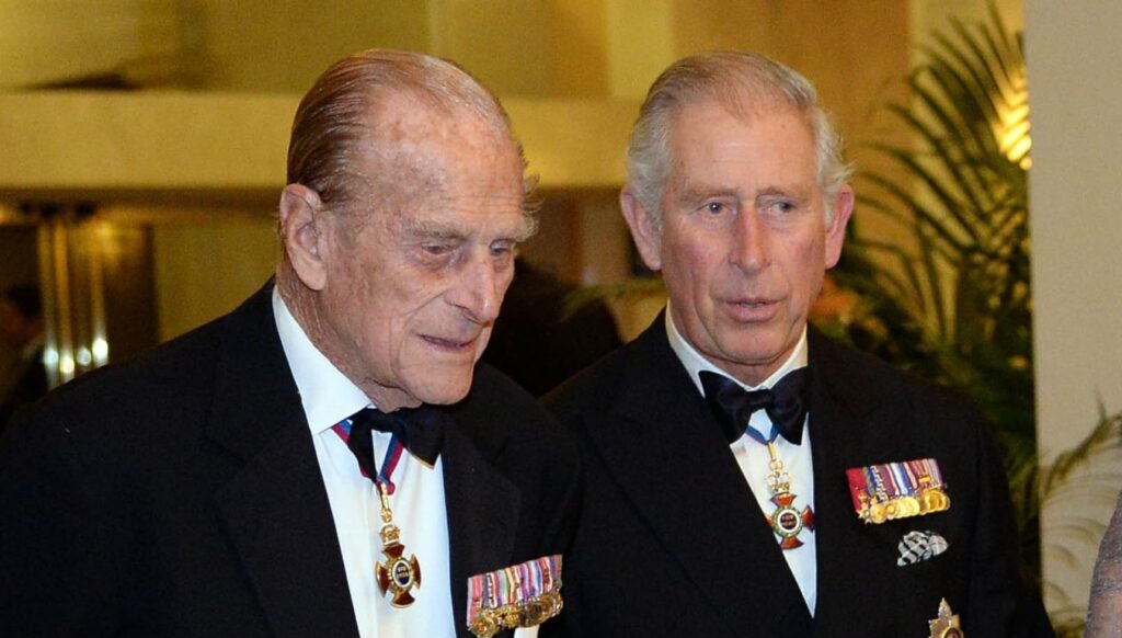 Prince Philip and Charles speaking in tuxedos
