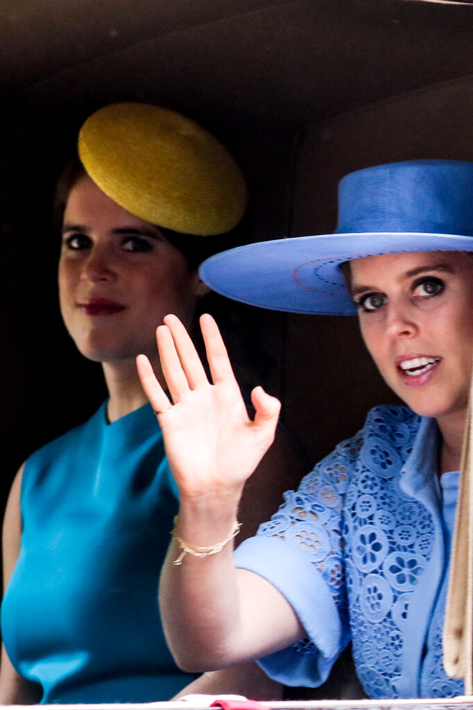 Princess Eugenie smiling beside Princess Beatrice waving