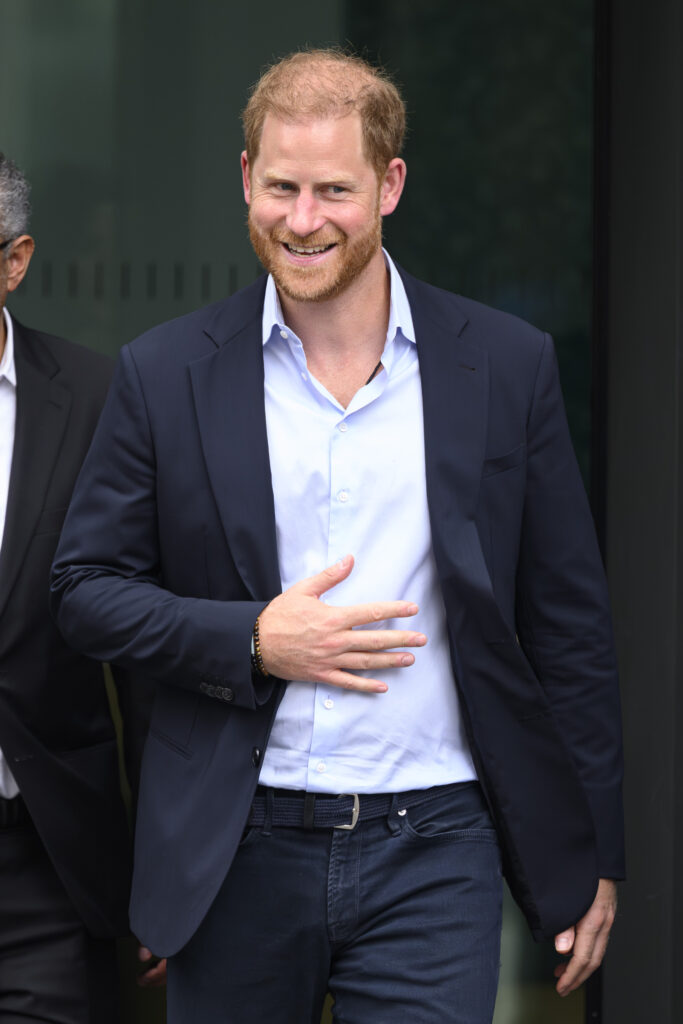 Prince Harry walking and smiling in suit