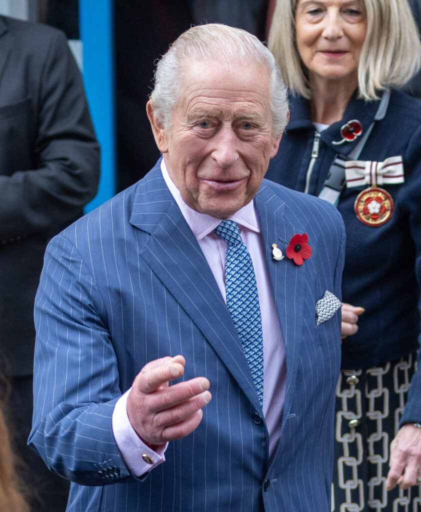 King Charles walking and pointing in blue suit