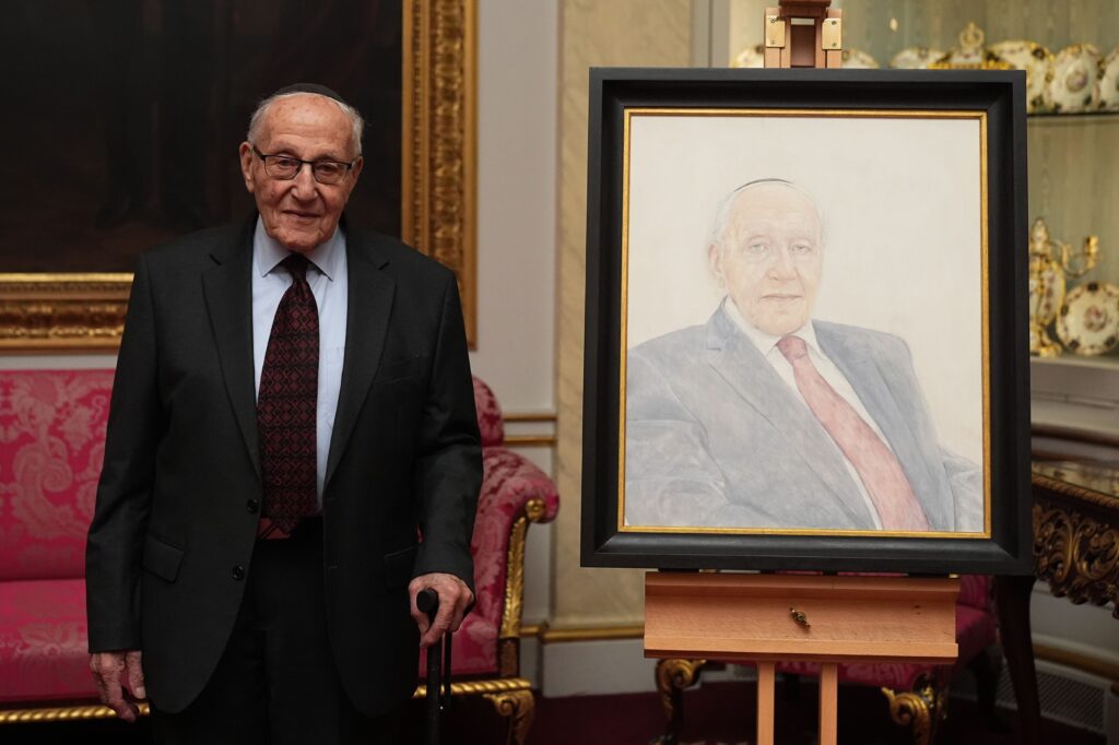 Manfred Goldberg next a portrait of himself at Buckingham Palace
