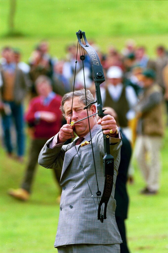 Prince Charles aiming a bow and arrow