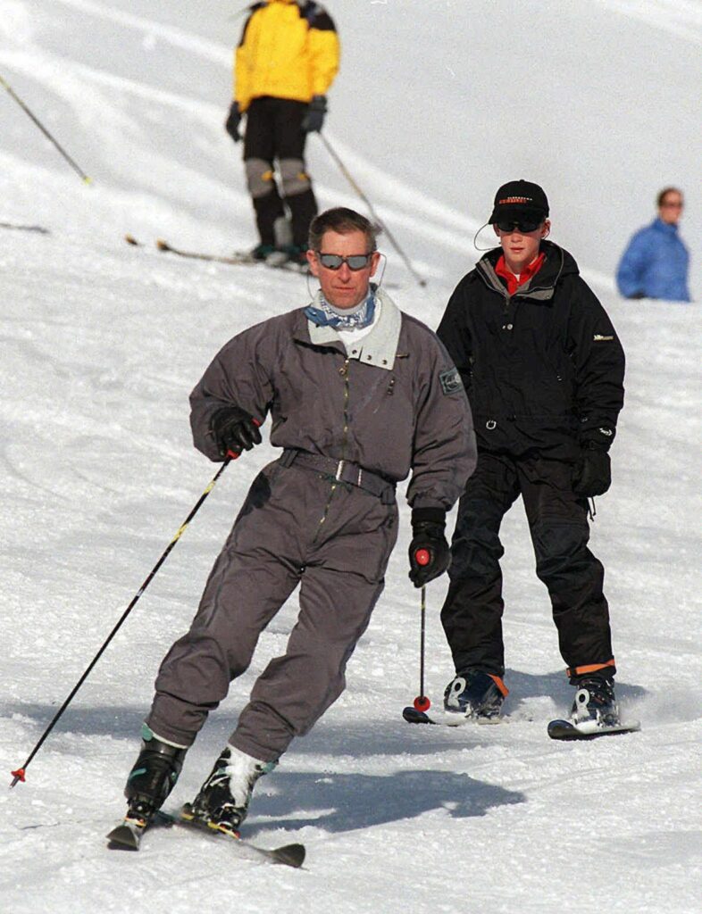 Prince Charles skiing down a slope at a Swiss Resort followed by Prince Harry