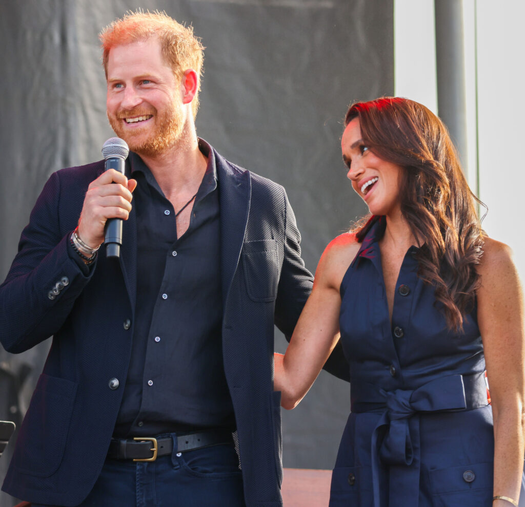 Prince Harry and Meghan Markle smiling on stage