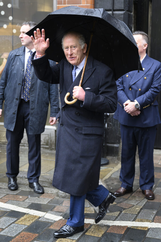 King Charles waving holding an umbrella
