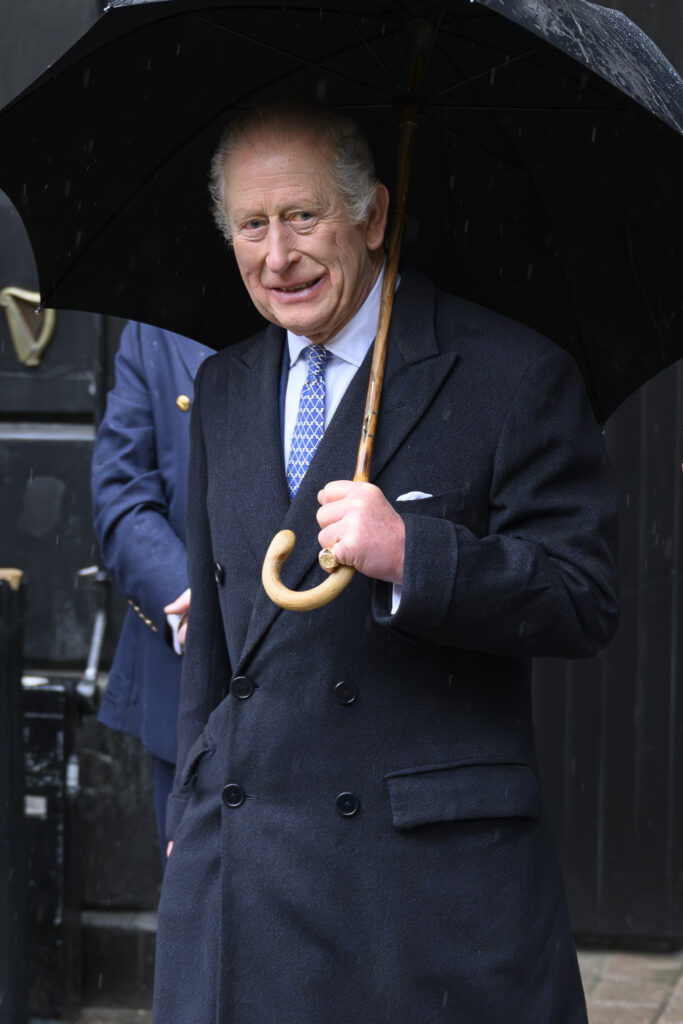 King Charles walking with umbrella