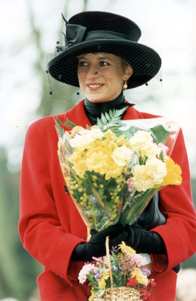 Princess Diana wearing a black hat and veil with a red coat on Christmas day in 1993