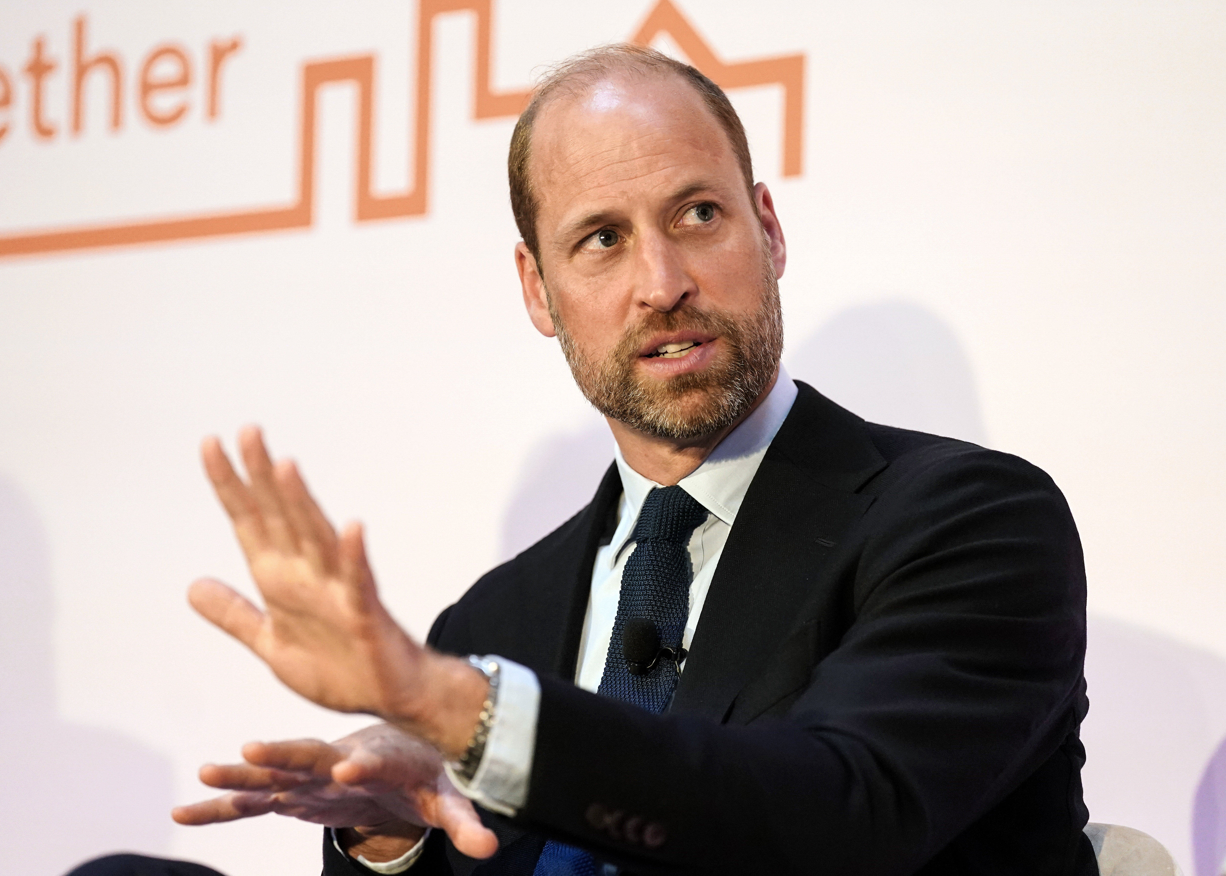 Prince William frowning with his hand up 