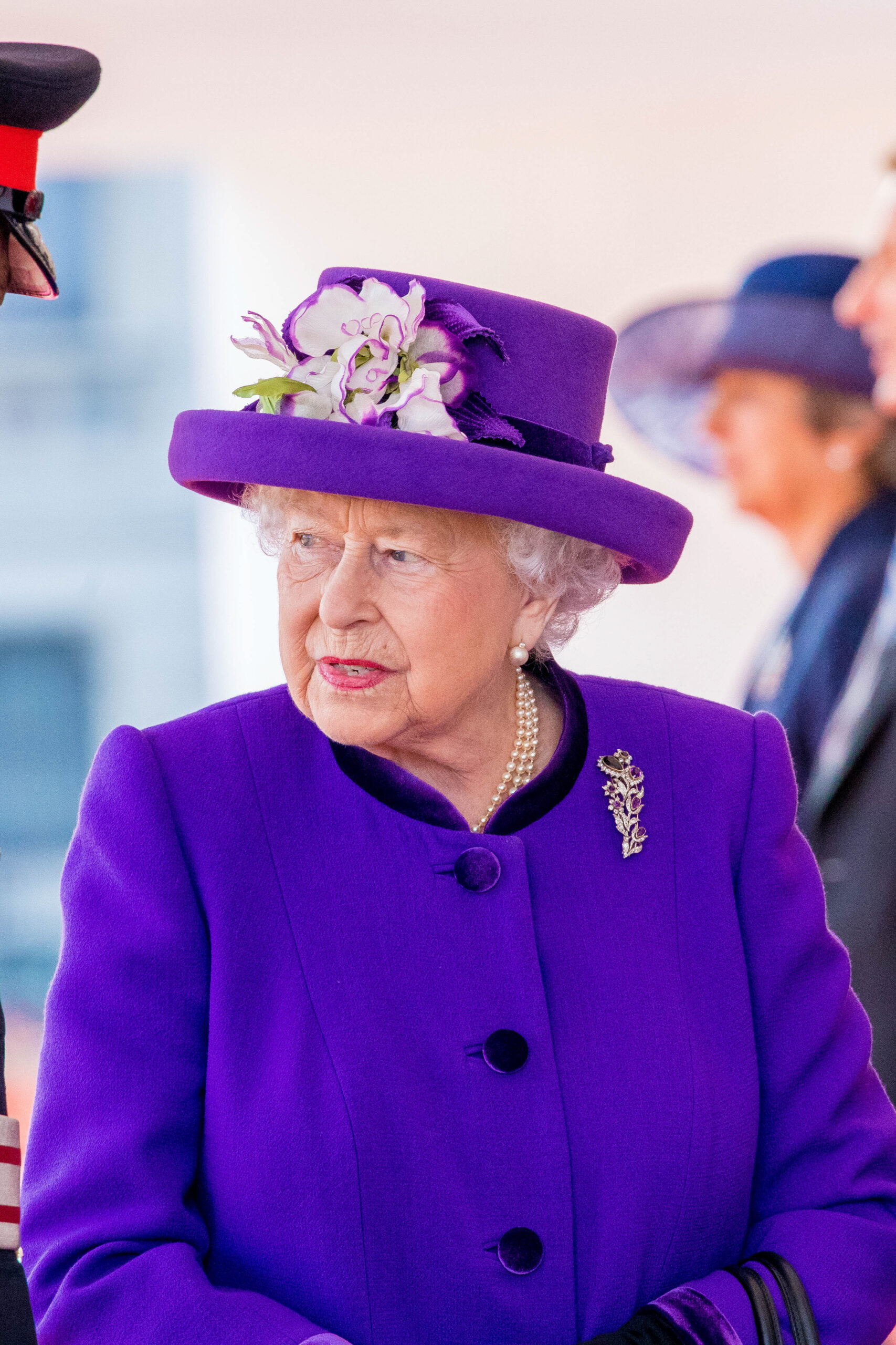 Queen Elizabeth frowning wearing a purple outfit