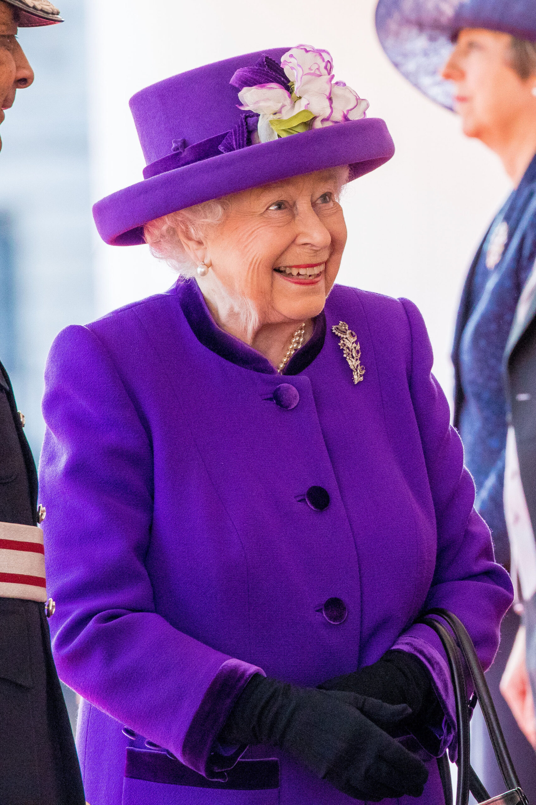 Queen Elizabeth smiling wearing a purple outfit