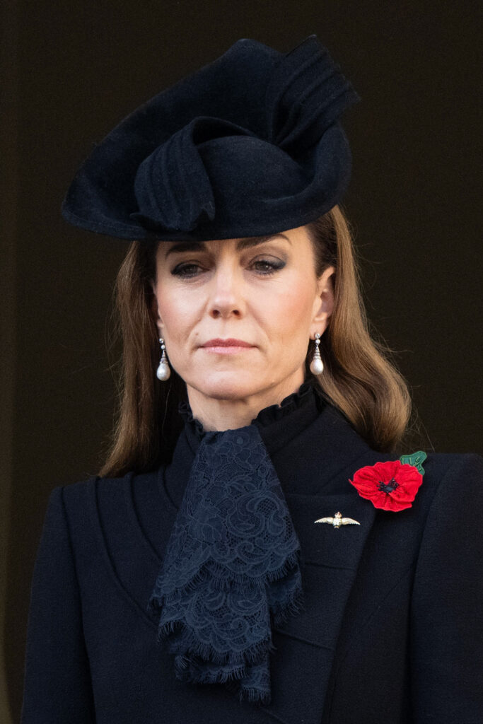 Princess Kate frowning wearing a black ensemble and hat