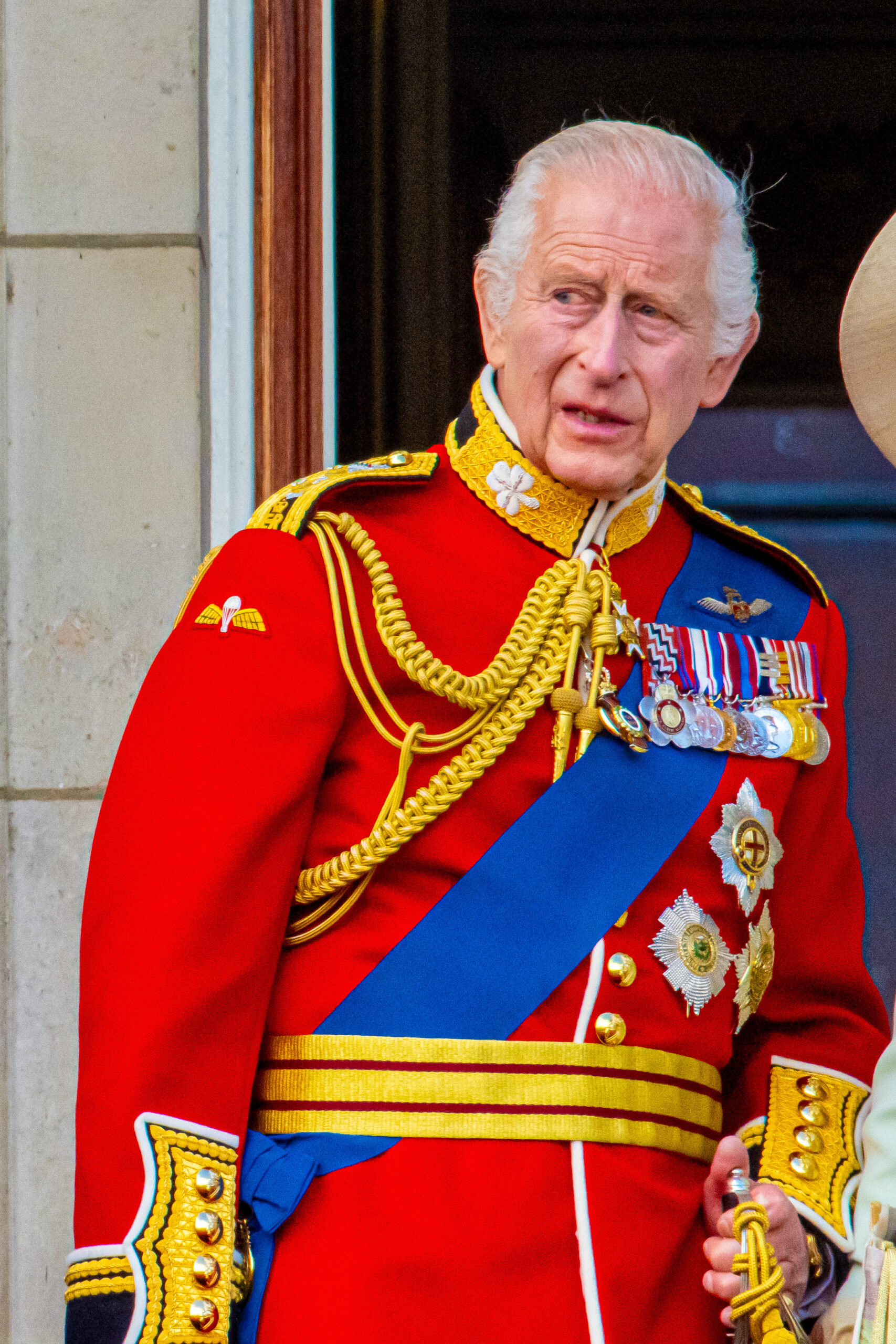 King Charle on Buckingham Palace balcony in Trooping the Colour regalia with a serious expression