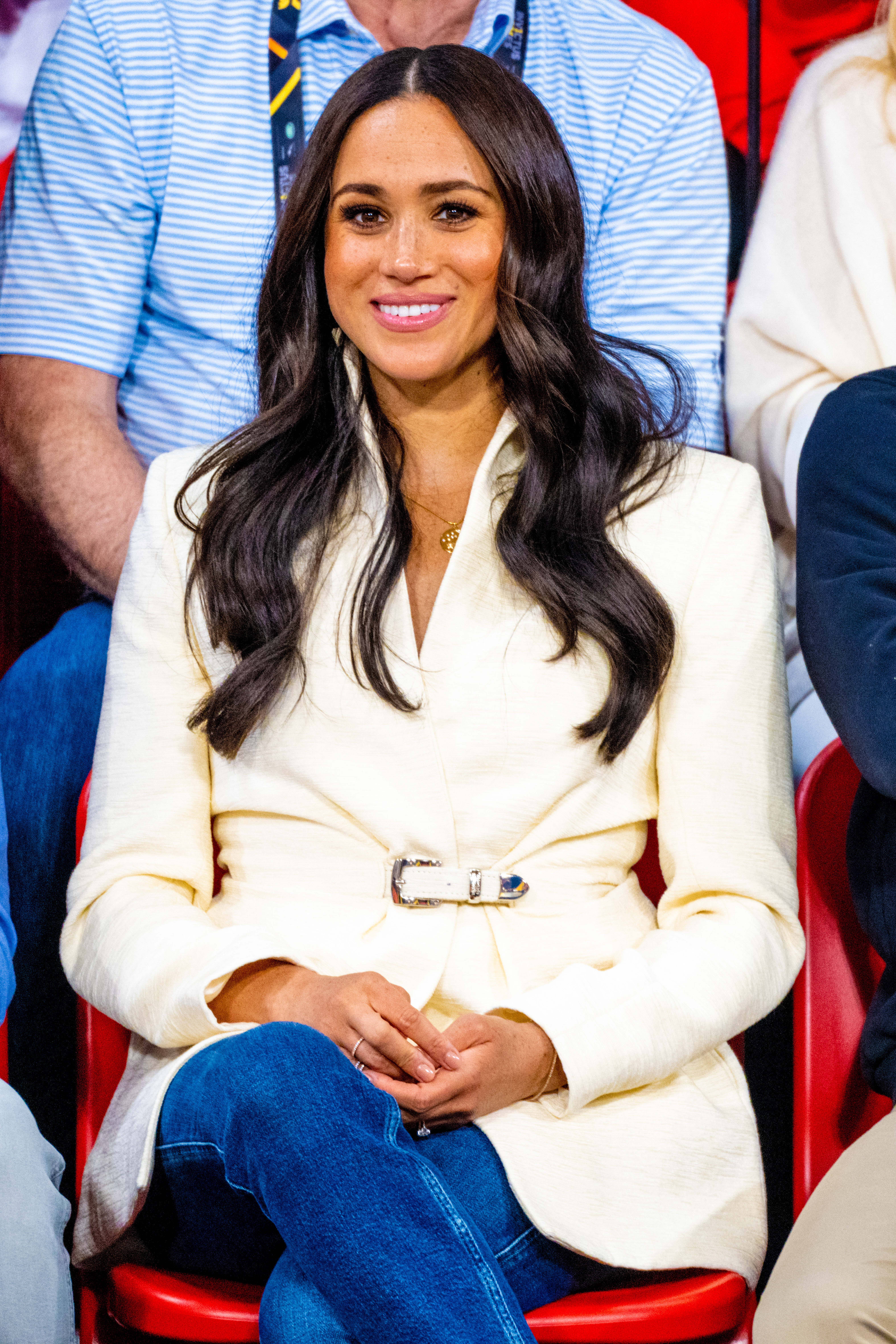Meghan Markle smiling wearing a white coat