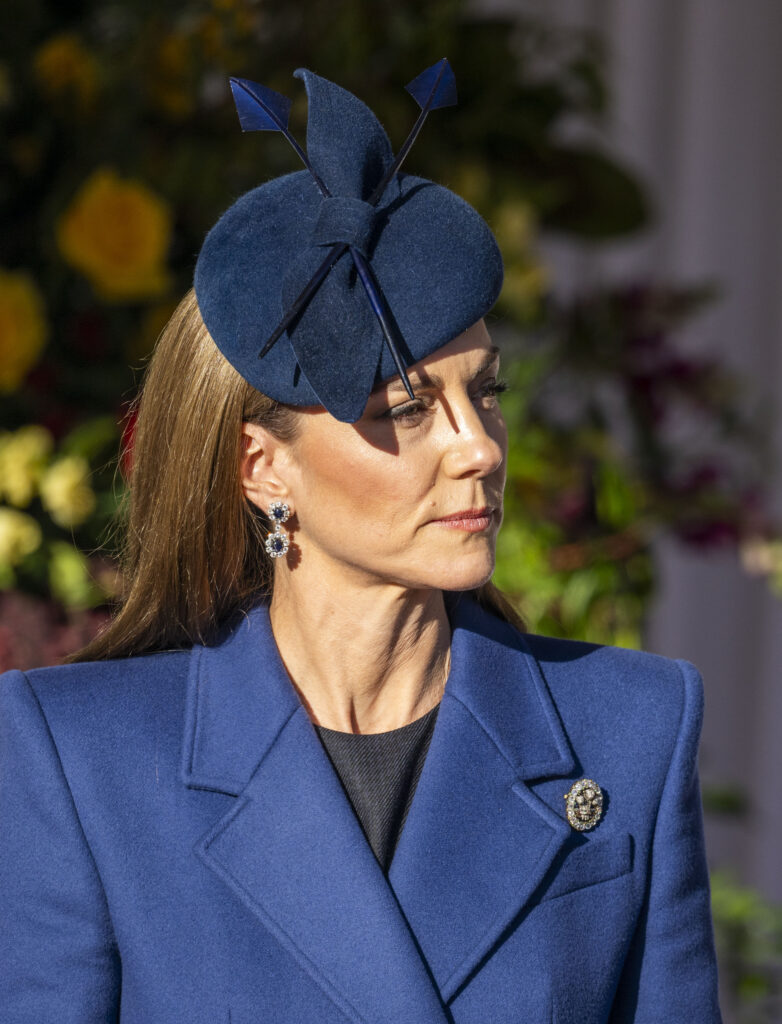 Princess Kate frowning wearing a blue ensemble and hat