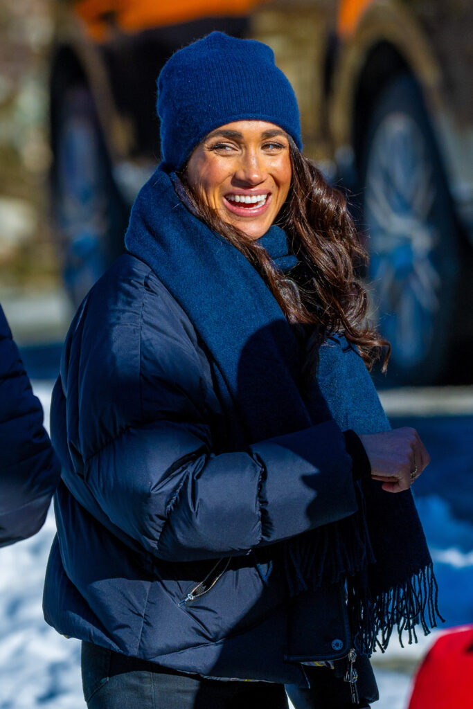 Meghan Markle wrapped up warm in a navy coat, hat and scarf, smiling