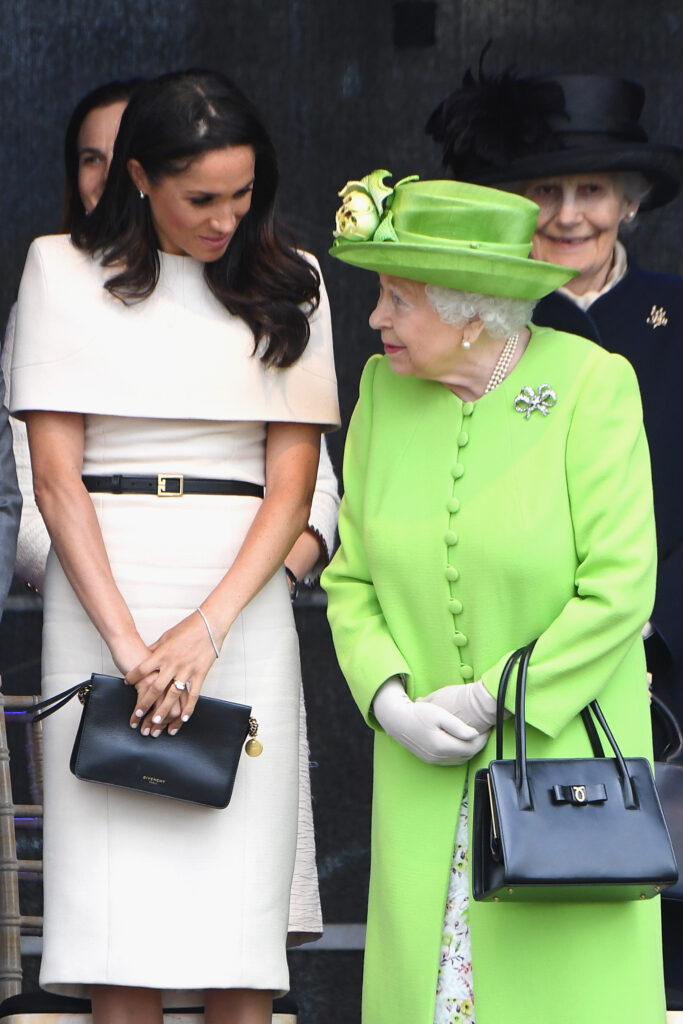 Meghan Markle wearing a white dress beside Queen Elizabeth wearing green