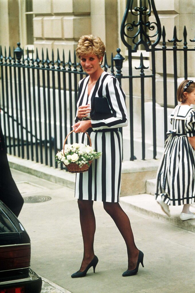 Princess Diana in a black and white striped suit holding flowers