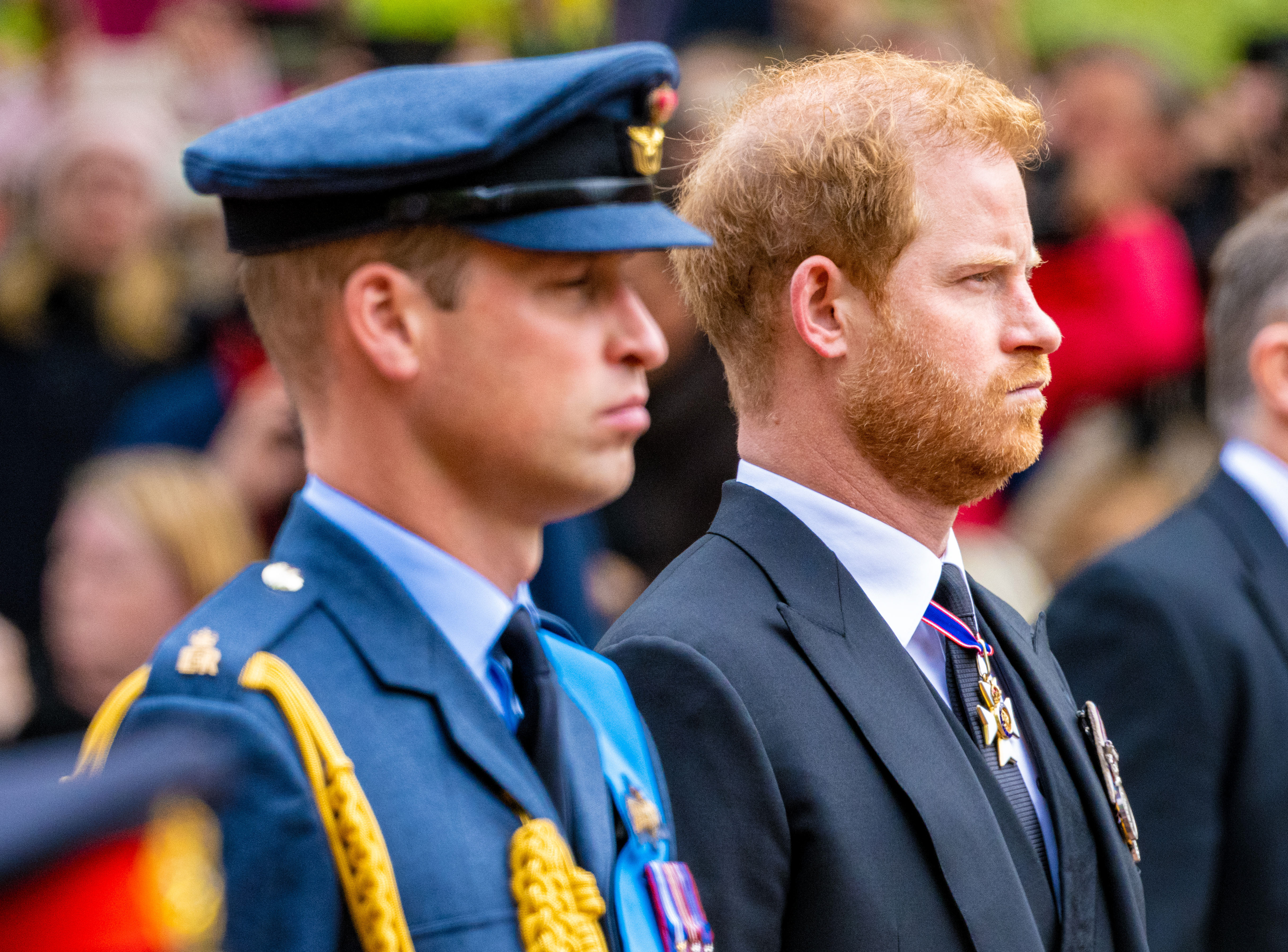 Prince William frowning besides Prince Harry, both wearing uniform