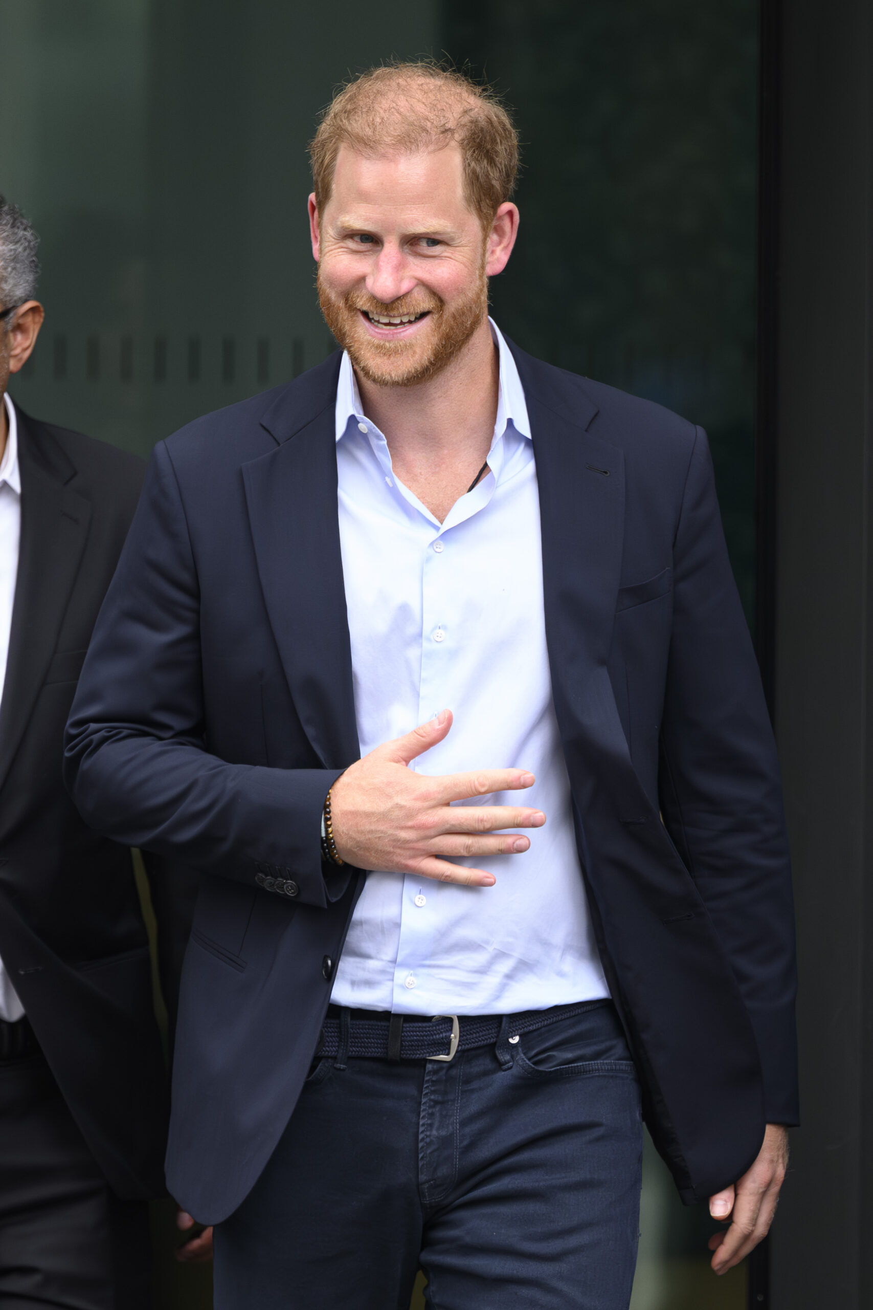 Prince Harry walking and smiling in black suit