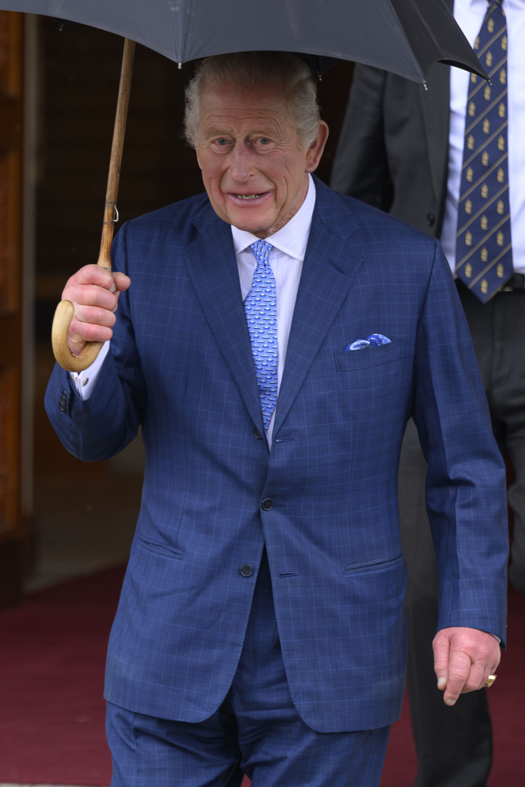 King Charles holding an umbrella in blue suit