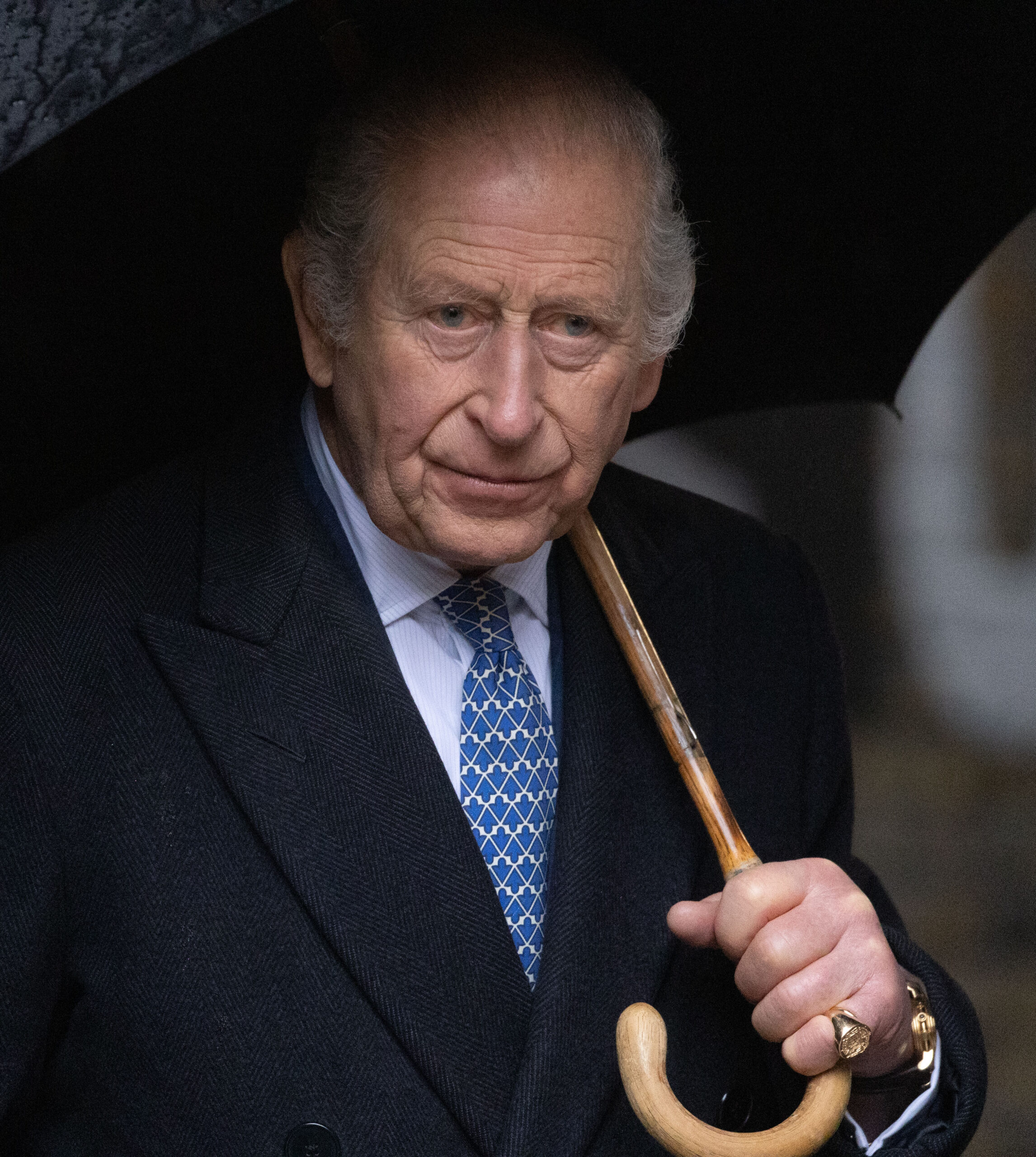 King Charles walking with umbrella