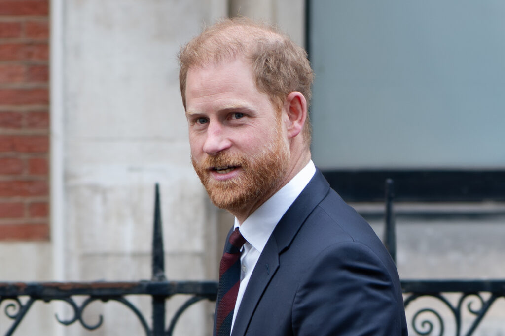 Prince Harry smiling in suit during UK return