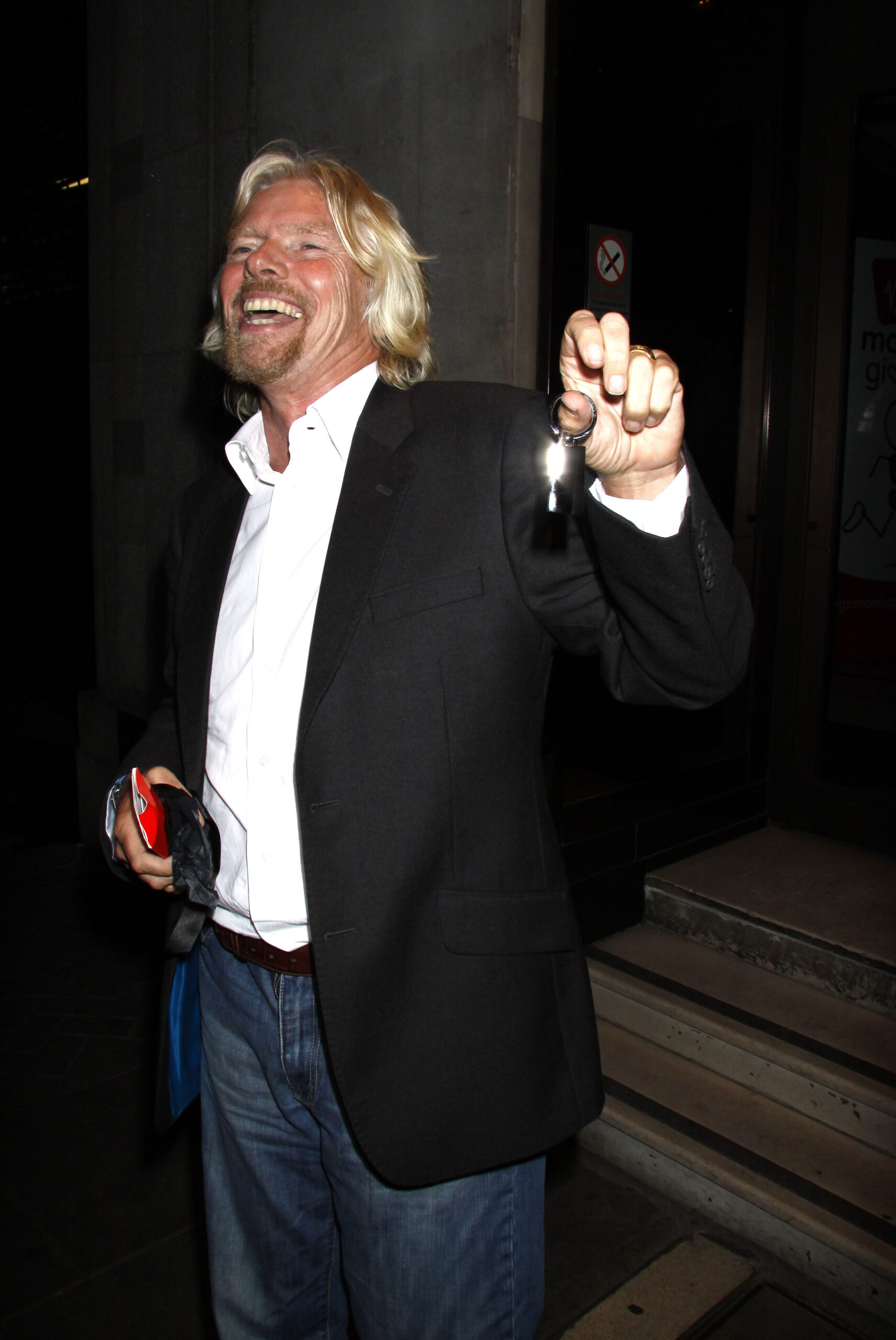 Richard Branson smiling and holding up a pair of keys in 2009