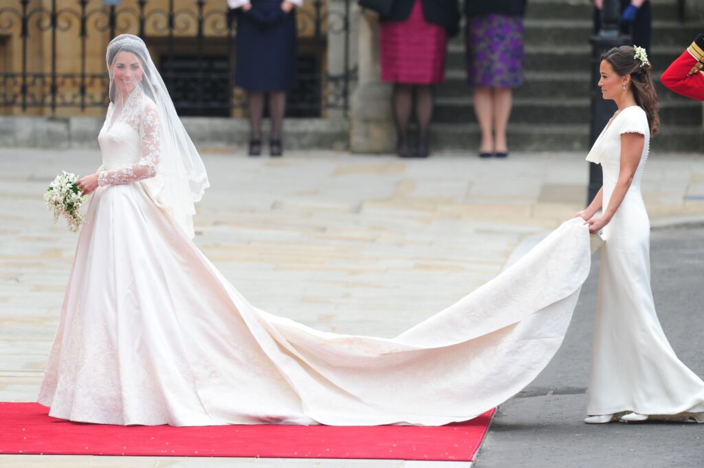 Princess Kate wearing a sweeping, Sarah Burton for Alexander McQueen wedding dress outside Westminster Abbey, Pippa Middleton holds her train