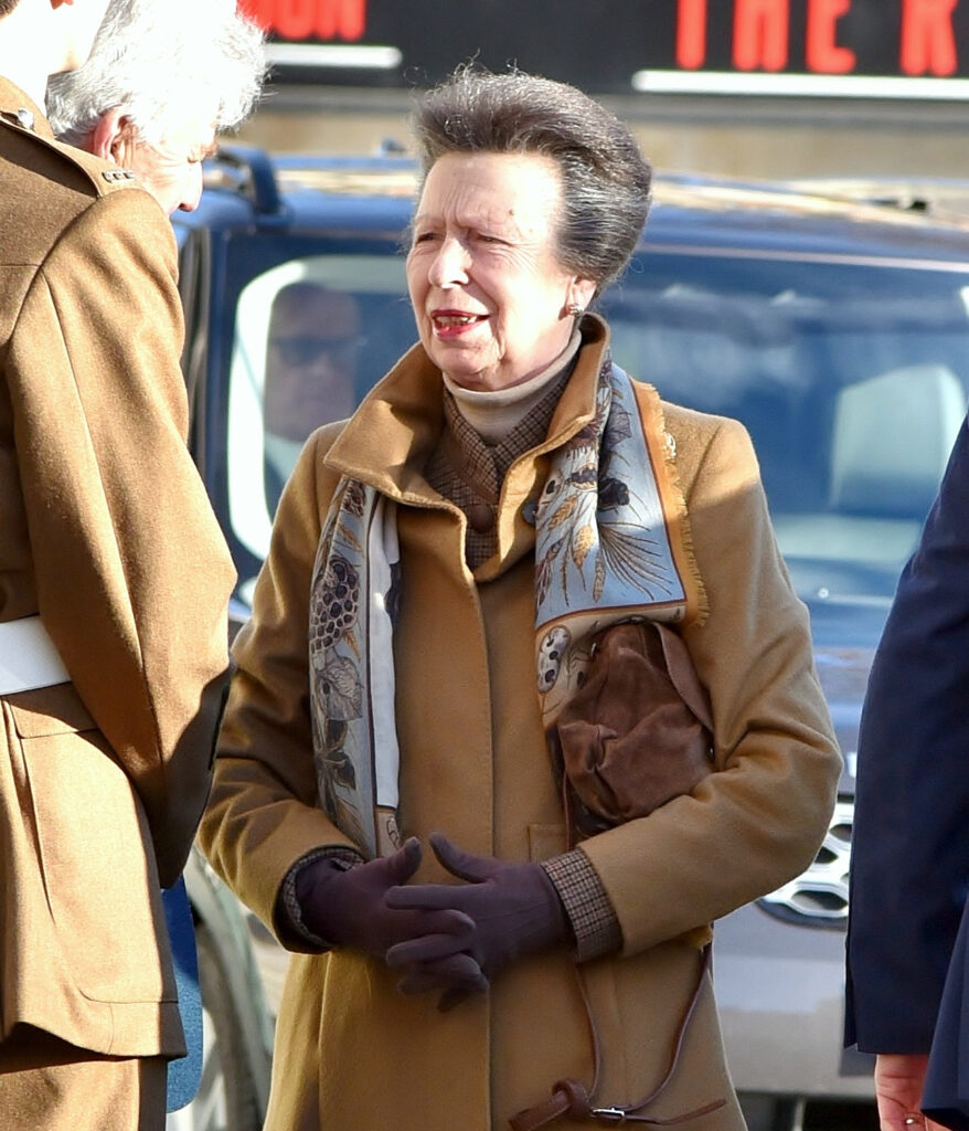 Princess Anne smiling, bundled up in a coat, scarf and gloves
