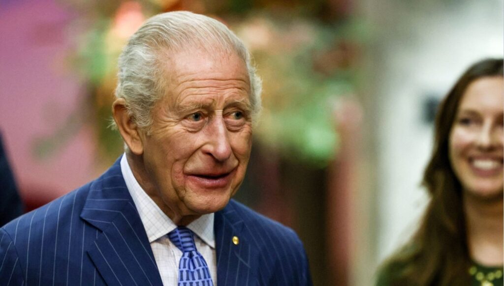 King Charles in blue suit, smiling