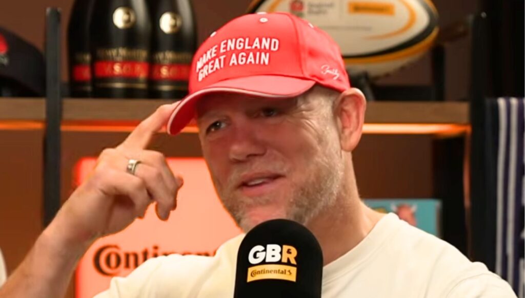 Mike Tindall pointing at a red Make England Great Again cap he is wearing