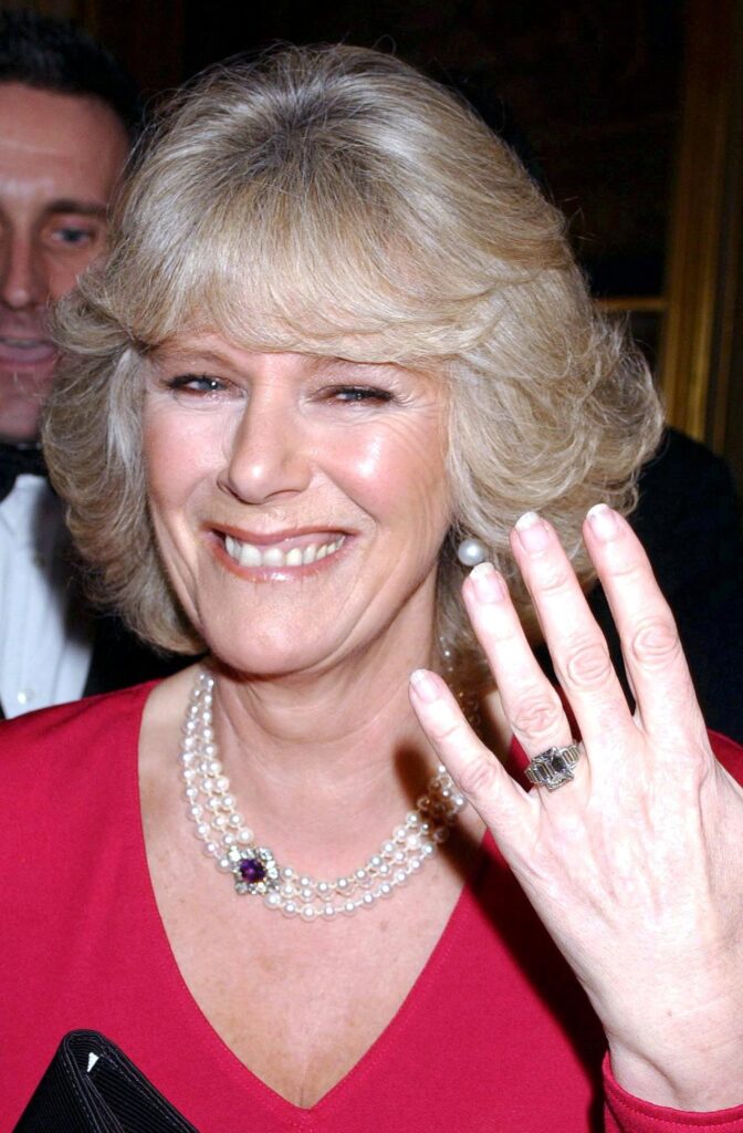 Queen Camilla smiling holding her hand aloft to show off her engagement ring