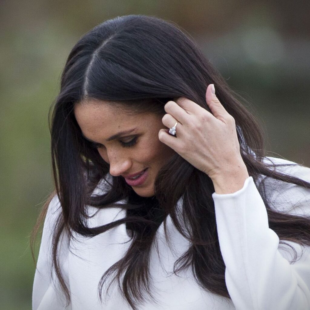 Meghan Markle smiling and touching her hair, showing off her engagement ring