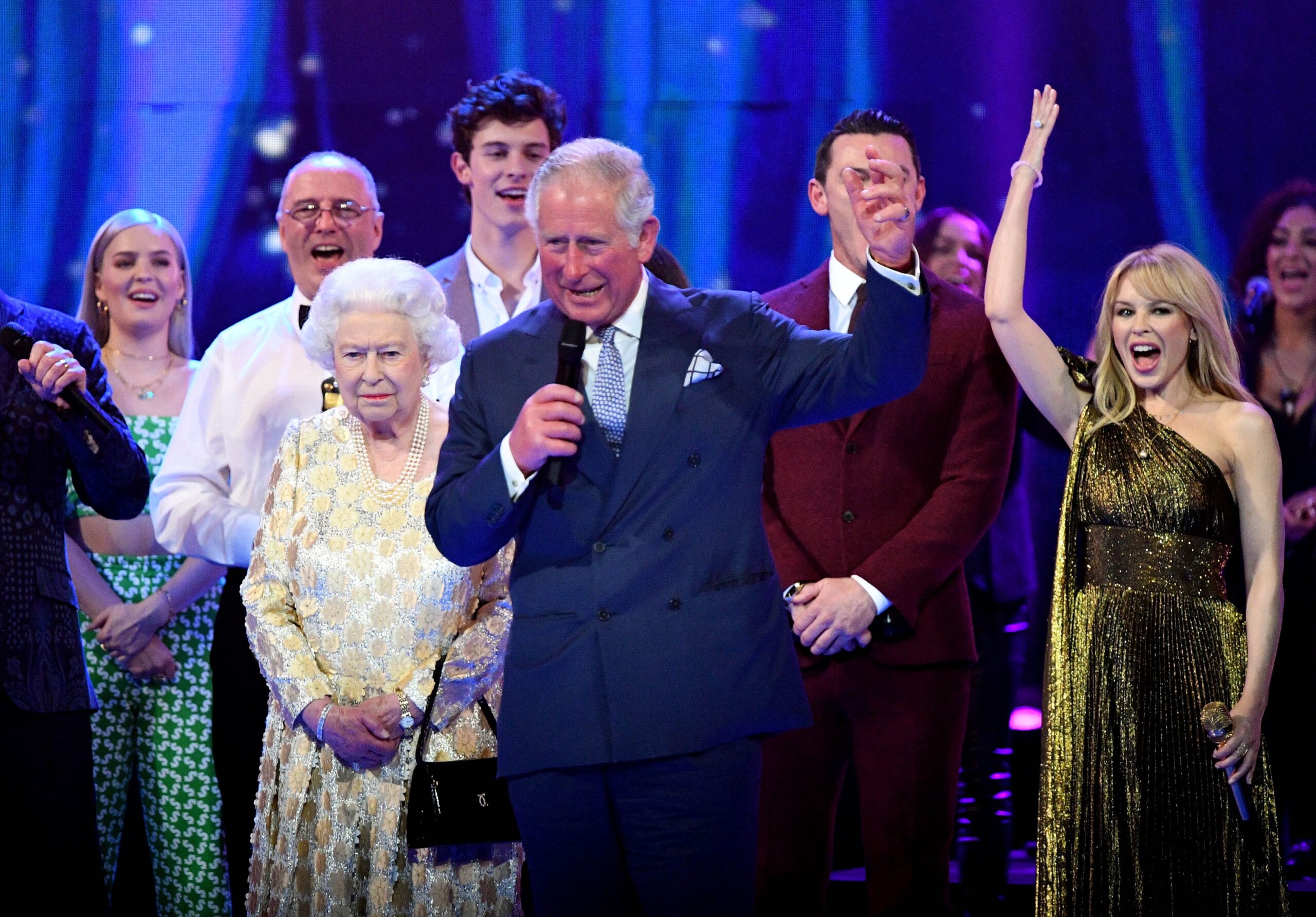 King Charles giving speech on stage next to Queen Elizabeth II