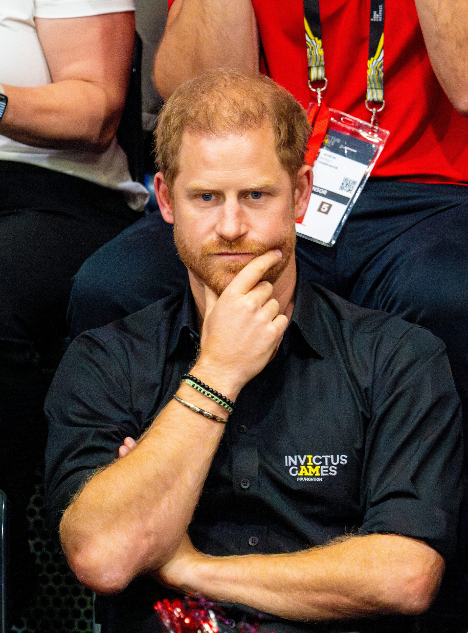 Prince Harry with his chin resting in his hand thoughtfully