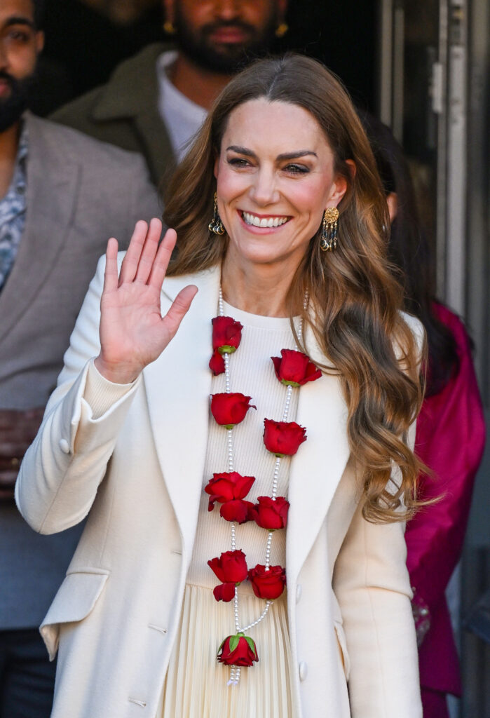 Princess Kate smiling and waving wearing a red rose garland