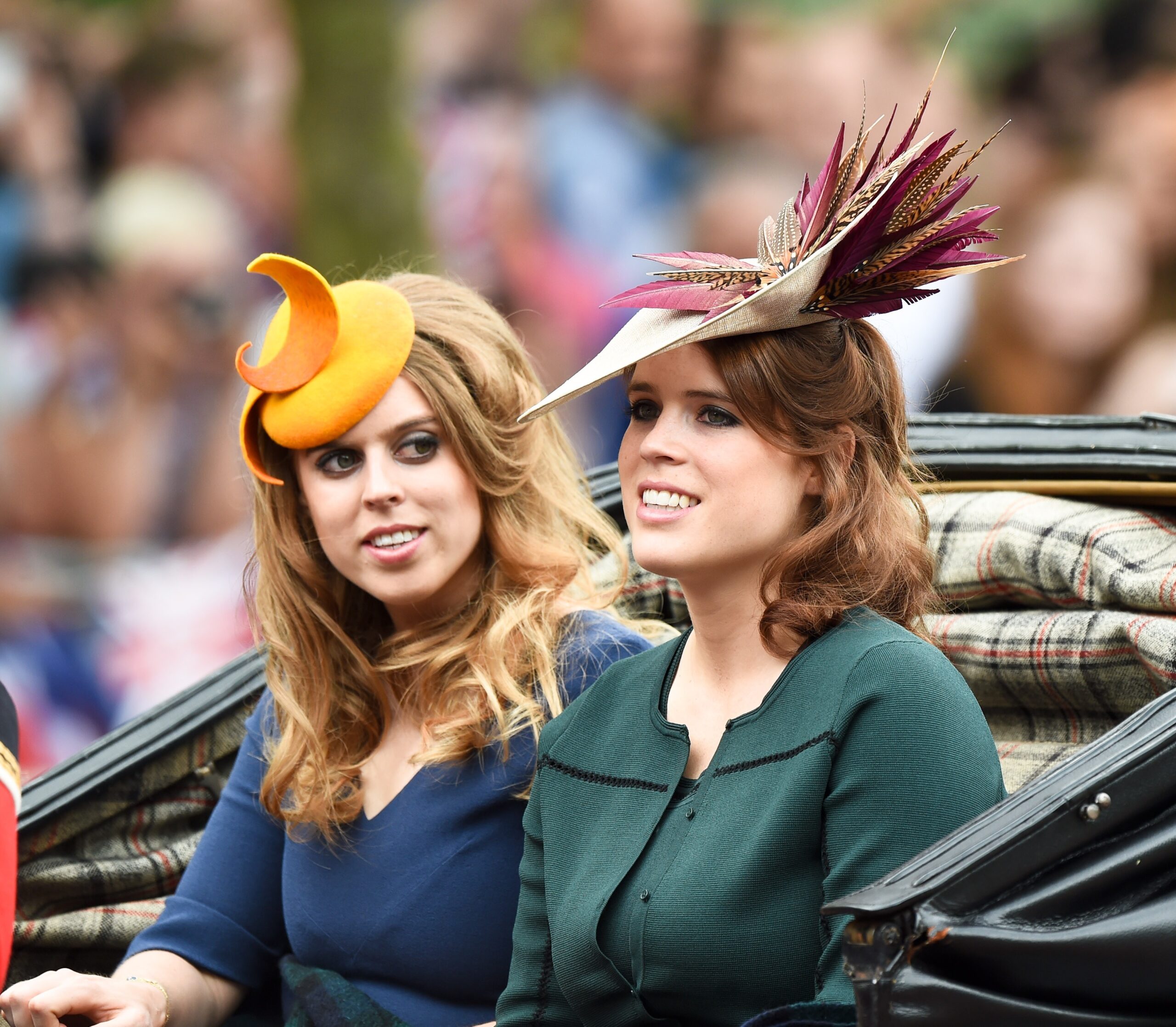 Princess Beatrice and Princess Eugenie wearing fancy hat in the back of a horse-drawn carriage