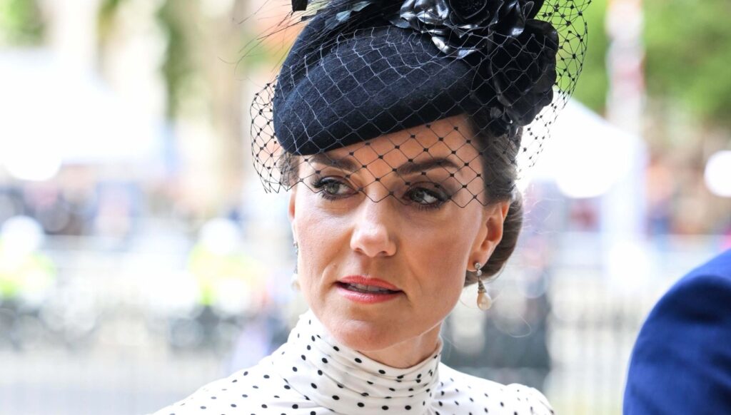 Princess Kate wearing a black hat looking serious