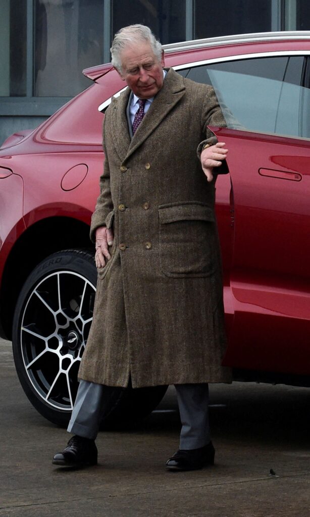 King Charles closing the door of a red car
